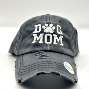 K&ouml;nnte beinhalten: Eine graue, abgenutzte Baseballkappe mit einem wei&szlig;en gestickten Pfotenabdruck und dem Text "DOG MOM".