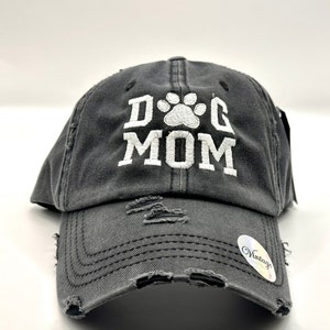 K&ouml;nnte beinhalten: Eine graue, abgenutzte Baseballkappe mit einem wei&szlig;en gestickten Pfotenabdruck und dem Text "DOG MOM".