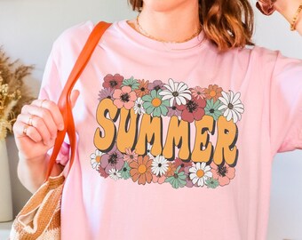 May include: A pink t-shirt with a floral design and the word "SUMMER" in yellow letters.