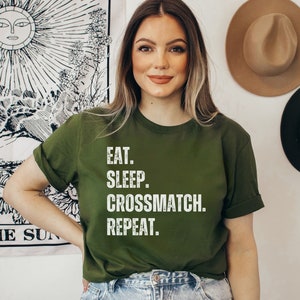 May include: A green t-shirt with white text that reads "Eat. Sleep. Crossmatch. Repeat."