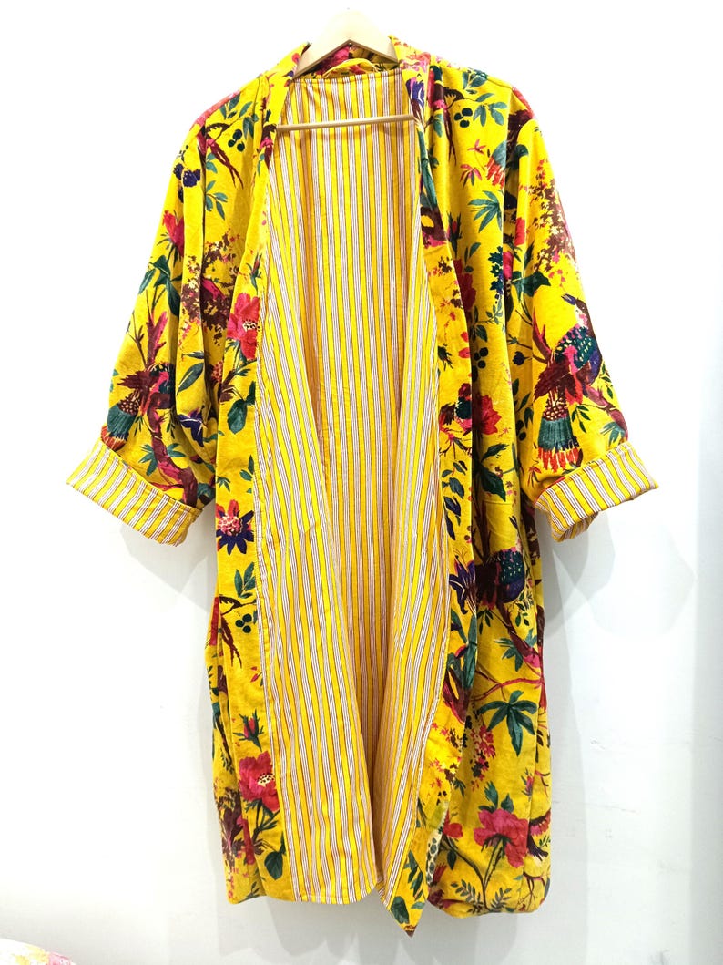 Puede incluir: Un kimono amarillo con estampado floral y de p&aacute;jaros. El kimono tiene un forro a rayas y est&aacute; abierto por delante.