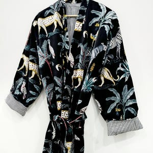 Puede incluir: Bata de terciopelo negro con estampado de jungla con leopardos, cebras y palmeras. La bata tiene un cintur&oacute;n a juego y ribetes a rayas en las mangas.