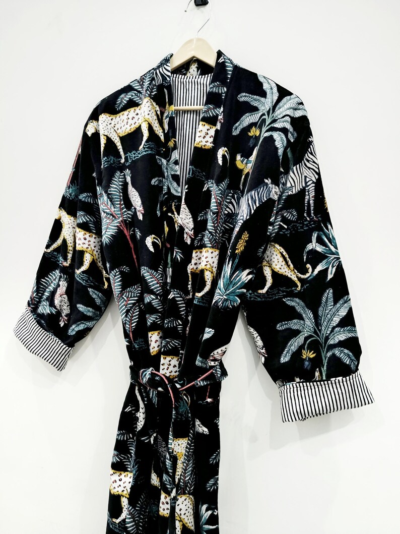 Puede incluir: Bata de terciopelo negro con estampado de jungla con leopardos, cebras y palmeras. La bata tiene un cintur&oacute;n a juego y ribetes a rayas en las mangas.