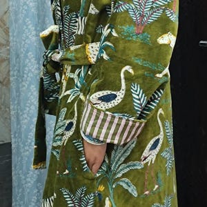 Puede incluir: Una bata de terciopelo verde con un estampado colorido de cebras, p&aacute;jaros y palmeras. La bata tiene un cintur&oacute;n de atar y bolsillos.