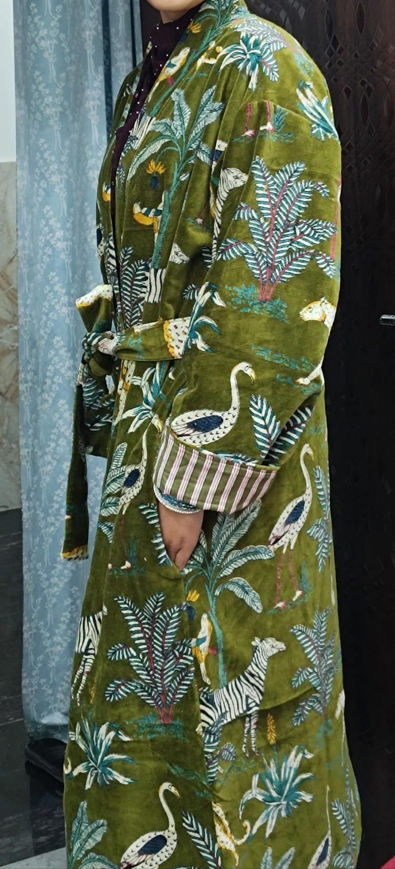 Puede incluir: Una bata de terciopelo verde con un estampado colorido de cebras, p&aacute;jaros y palmeras. La bata tiene un cintur&oacute;n de atar y bolsillos.