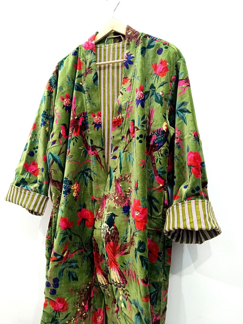 Puede incluir: Una bata de terciopelo verde con estampado floral con p&aacute;jaros y flores. La bata tiene un forro a rayas y un cuello chal.