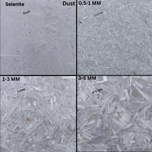 May include: Close-up image of selenite crystals in various sizes, ranging from dust to 3-5 mm. The image shows the different sizes of the crystals, with the smaller crystals appearing as a white powder and the larger crystals appearing as long, thin needles.