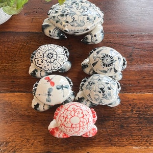 May include: Five ceramic crab figurines with blue and white floral designs. One crab has a red and white floral design.