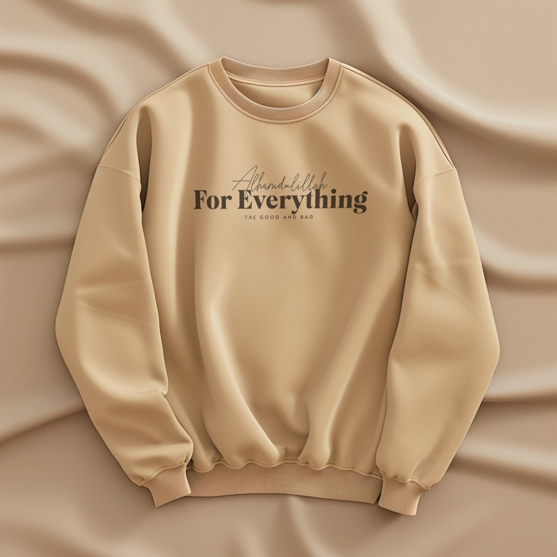 May include: A tan sweatshirt with the text "Alhamdulillah For Everything The Good and Bad" printed on the front.