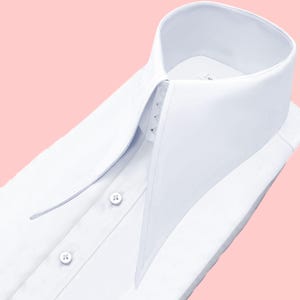 May include: A crisp white dress shirt with a high, pointed collar. The shirt is buttoned up and neatly folded, showcasing the tailored design. The collar is the focal point, with its sharp angles and clean lines.