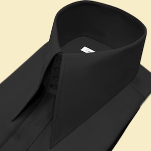 Puede incluir: Una camisa negra de vestir con cuello puntiagudo y cierre de botones. El cuello tiene un diseño único con una solapa puntiaguda a cada lado.
