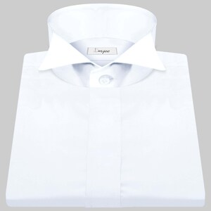 May include: A white dress shirt with a wide, pointed collar and a single button closure. The shirt has a label that reads "Dorjee".