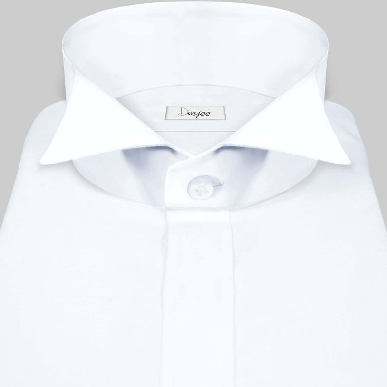 May include: A white dress shirt with a button-down collar and a single button closure. The shirt has a label that reads "Darjee".