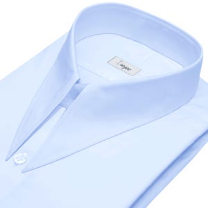 May include: A light blue dress shirt with a pointed collar and a single button closure. The shirt has a label that reads "Darjee".