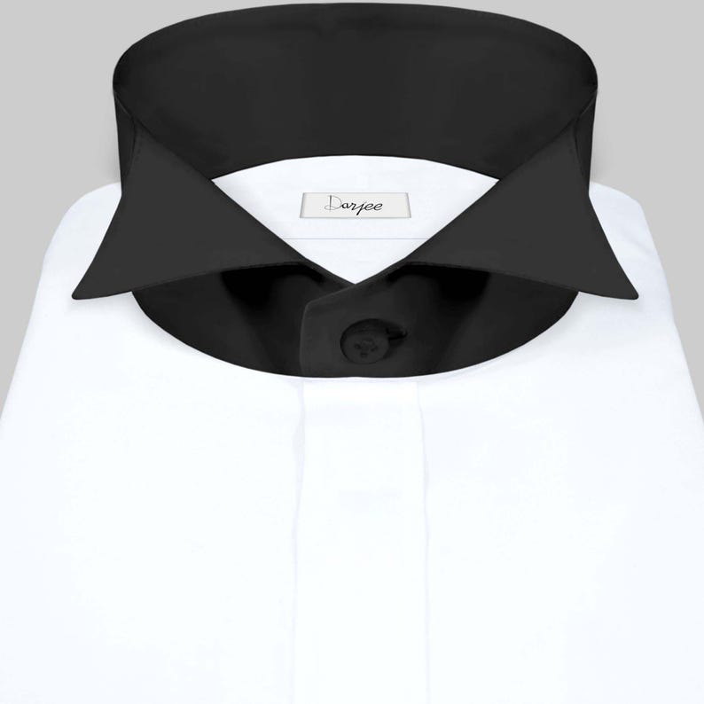 May include: A white dress shirt with a black collar and a single black button. The shirt has a label that says "Darjee".