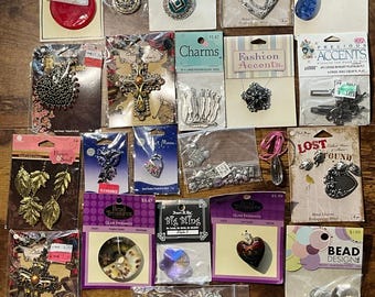 May include: A collection of jewelry-making supplies, including pendants, charms, and beads. Various shapes and colors are visible, such as hearts, leaves, and crosses. Packages display text like "Fashion Accessories" and "Bead Treasures."