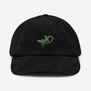 Può includere: Un cappello da baseball in velluto a coste nero con una lucertola verde ricamata con macchie blu.