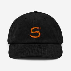 May include: A black corduroy baseball cap with an orange snake embroidered on the front. The snake is curled into the shape of the letter "S".