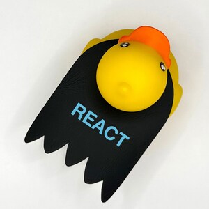 Op de afbeelding: Een gele rubberen eend met een zwart-wit haarstuk en het woord "REACT" erop.