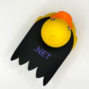 K&ouml;nnte beinhalten: Eine gelbe Gummiente mit einem schwarzen Umhang und dem Text ".NET" auf dem Umhang.