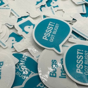 May include: A close-up of several teal blue and white round stickers with the text "PSSST! GOT BUGS?" printed on them. The stickers are arranged in a pile, with some overlapping.
