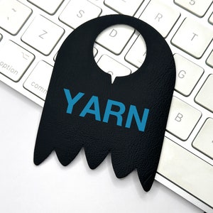 May include: A black leather door hanger with a cut-out for a door knob. The hanger has a jagged bottom edge and the word "YARN" printed in blue letters.