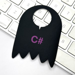 May include: Black leather door hanger with a cut-out for a door knob and the text "C#" in pink.