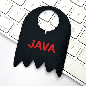 Puede incluir: Un colgador de puerta de cuero negro con un recorte para colgar y la palabra "JAVA" en letras rojas.