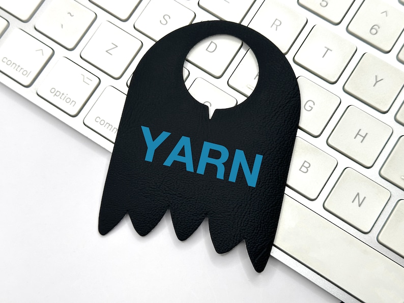 May include: A black leather door hanger with a cut-out for a door knob. The hanger has a jagged bottom edge and the word "YARN" printed in blue letters.