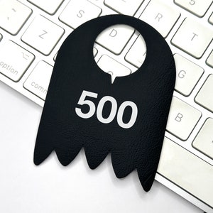 May include: A black leather door hanger with a cut-out hole at the top and the number 500 printed in white on the front. The hanger is sitting on a white keyboard.