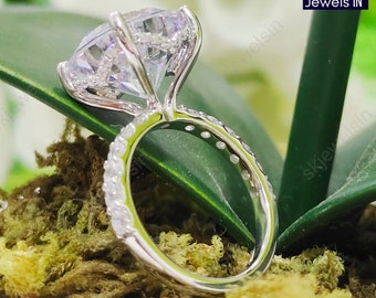 Puede incluir: Un anillo de plata con una gran piedra de circonita cúbica redonda y transparente engastada en garras. La banda está adornada con piedras de circonita cúbica más pequeñas.