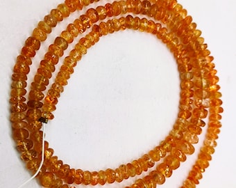 May include: A strand of orange sunstone beads. The beads are small and round, and they have a slightly iridescent sheen.