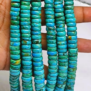 May include: Strands of turquoise beads, each a disc shape, in varying shades of blue and green. The beads are strung together, creating a necklace or bracelet. The turquoise beads are approximately 0.5 cm in diameter.