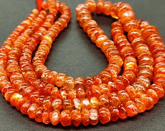 May include: A strand of orange sunstone beads. The beads are faceted and have a shimmery, iridescent finish.