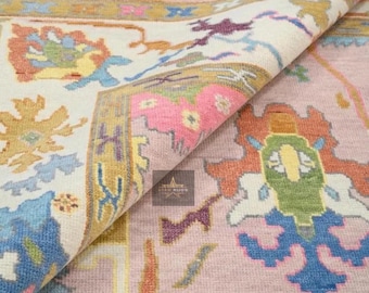 May include: A close-up of a pink and white rug with a floral pattern. The rug has a detailed design with intricate details in shades of blue, green, yellow, and orange.