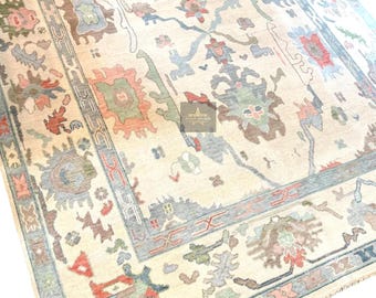 May include: A beige rug with a traditional Persian design. The rug features intricate patterns in shades of blue, green, red, and brown. The rug has a fringed edge.