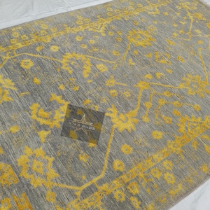 Puede incluir: Una alfombra de color gris y amarillo con un diseño floral. La alfombra tiene un brillo sutil y una textura suave.