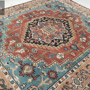 May include: A traditional Persian rug with a central medallion in shades of red, blue, and beige. The rug has a detailed floral and geometric pattern.