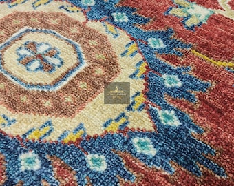 May include: Close-up of a red, blue and yellow patterned rug with a detailed design. The rug has a traditional, woven look and feel.