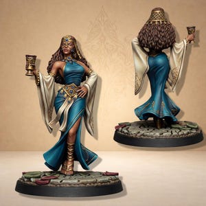 Może przedstawiać: Szczegółowa miniaturowa figurka kobiety w turkusowej sukni ze złotymi akcentami, trzymającej kielich. Figurka ma długie brązowe włosy i jest ozdobiona złotą biżuterią. Podstawa jest ciemnoszara o teksturowanym wyglądzie.