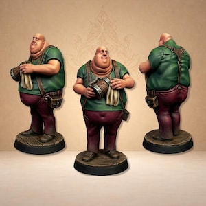 Könnte beinhalten: Eine bemalte Miniaturfigur eines kahlköpfigen, stämmigen Charakters mit grünem T-Shirt, dunkelroter Hose und braunen Hosenträgern. Die Figur hält einen Holzkrug und ein weißes Tuch und steht auf einem runden Holzsockel, aus drei Winkeln.