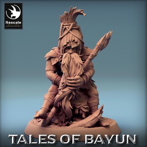 Può includere: Figura in miniatura marrone di un personaggio fantasy, con una lancia e una lunga barba. La figura indossa un'armatura e un copricapo. La base della figura riporta la scritta "TALES OF BAYUN". Il logo Rescale Miniatures si trova in alto a sinistra.