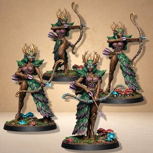 Könnte beinhalten: Vier Miniatur-Fantasy-Figuren von Bogenschützen. Jede Figur ist eine Elfe mit holzartiger Textur, grüner und violetter blattartiger Kleidung sowie Pfeil und Bogen. Die Figuren stehen auf Sockeln mit Miniaturpilzen und -laub.