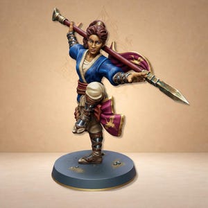 Peut inclure: Figurine détaillée d'un guerrier en pose dynamique, tenant une lance. La figurine porte une tunique bleue, un pantalon beige et des accents bordeaux. La base est un cercle gris foncé. La lance est tenue en biais, suggérant l'action.