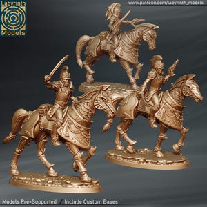 Könnte beinhalten: Drei goldfarbene Miniaturfiguren von berittenen Soldaten. Jeder Soldat trägt eine Rüstung und hält eine Waffe. Die Pferde sind ebenfalls mit dekorativer Rüstung geschmückt. Die Basis jeder Figur ist eine strukturierte, ovale Form. Der Text "Models Pre-Supported / Include Custom Bases" steht unten.