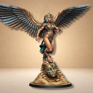 Pode incluir: Estatueta detalhada de uma mulher alada em traje verde-azulado e dourado, em pé sobre uma cabeça de esfinge esculpida. A figura tem asas grandes e detalhadas e está em uma pose dinâmica. A base tem uma forma circular escura.