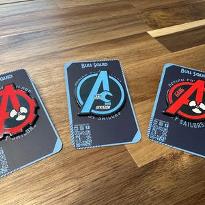 May include: Three black and white enamel pins with red accents. Each pin features a stylized letter 'A' with a propeller and the text 'Gang Division' and 'Bull Squid'.