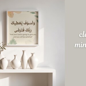 Pu&ograve; includere: Una stampa incorniciata con calligrafia araba e traduzione inglese, esposta sopra una mensola bianca. La mensola contiene diversi vasi di ceramica bianca e un vaso con vegetazione. Le parole "clean minimal" sono scritte sul muro.