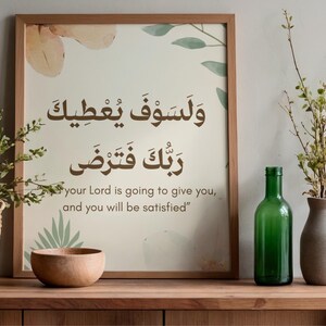 Pu&ograve; includere: Una stampa incorniciata con calligrafia araba e testo inglese: "il tuo Signore ti dar&agrave;, e sarai soddisfatto". L'immagine &egrave; su una superficie di legno con una bottiglia verde, un vaso e un cesto intrecciato con vegetazione.