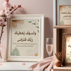 Pu&ograve; includere: Opera d'arte incorniciata con calligrafia araba e traduzione inglese, con accenti floreali e di foglie. L'opera d'arte &egrave; esposta con un vaso di fiori rosa e un bicchiere di champagne, creando una scena serena e decorativa.